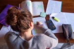 Student studying at table, a-level revision papers