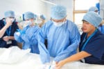 Doctors stand over a table