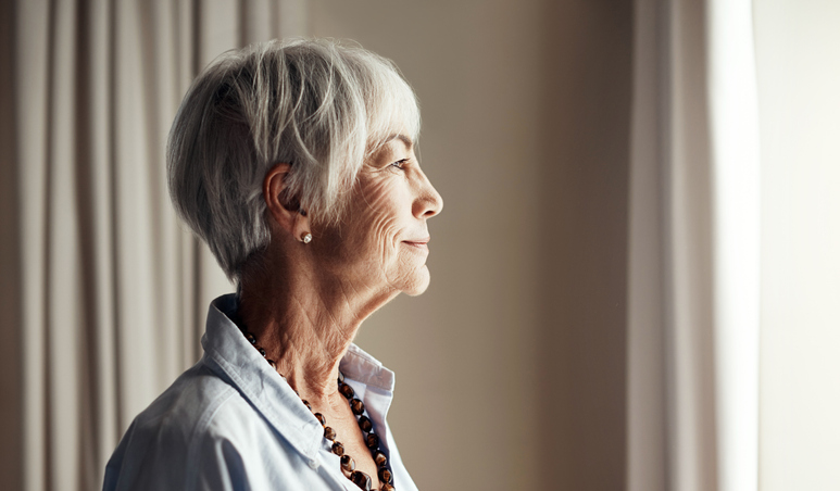 An elderly woman looks out of a window